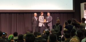 Image of participants and their innovative projects at the 2018 Merlion Competition in Singapore, emphasizing technology and creativity.