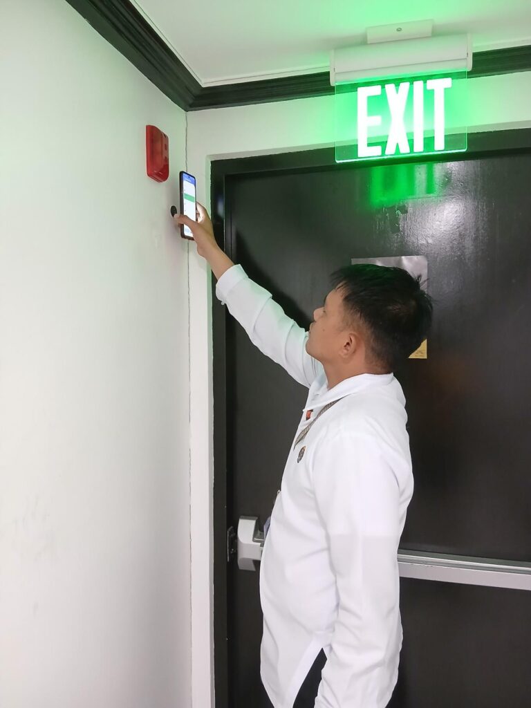 Security officer performing real-time guard tour inspection using mobile iREP system at building emergency exit